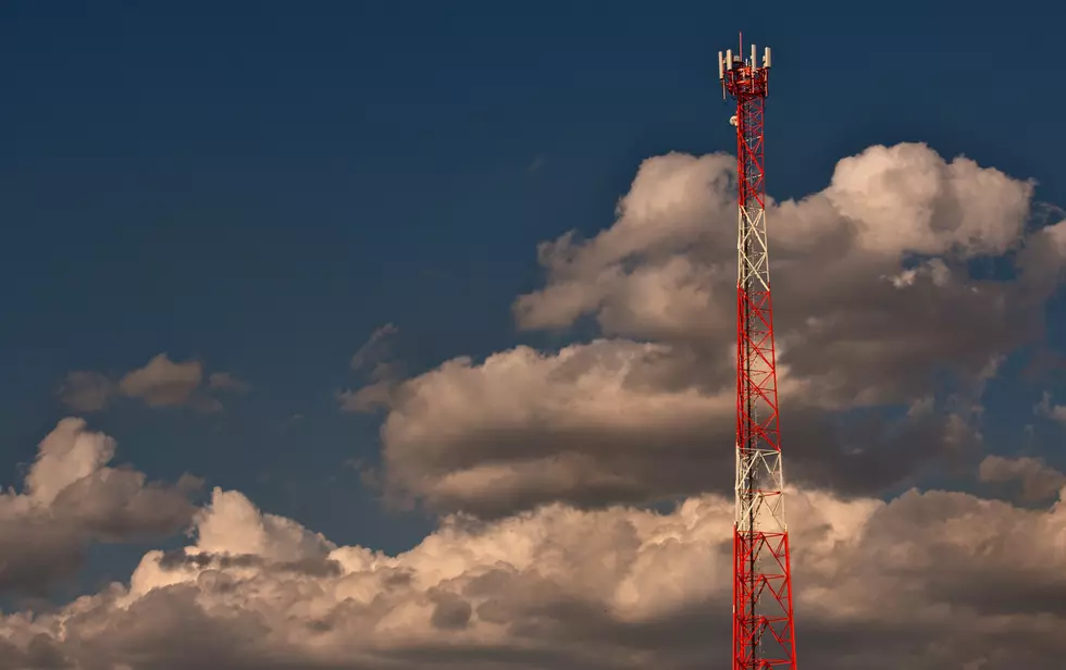 white and orange cell tower with sky and clouds background